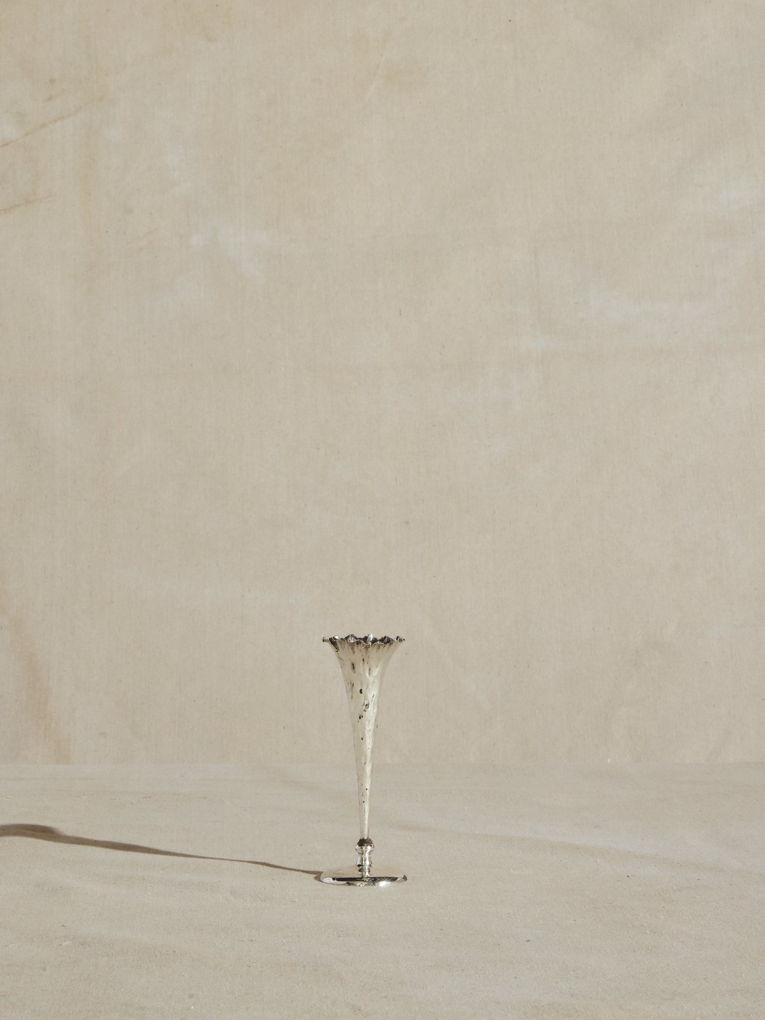 Slender sterling silver plated trumpet vase, with hammered body and wavy rim.
