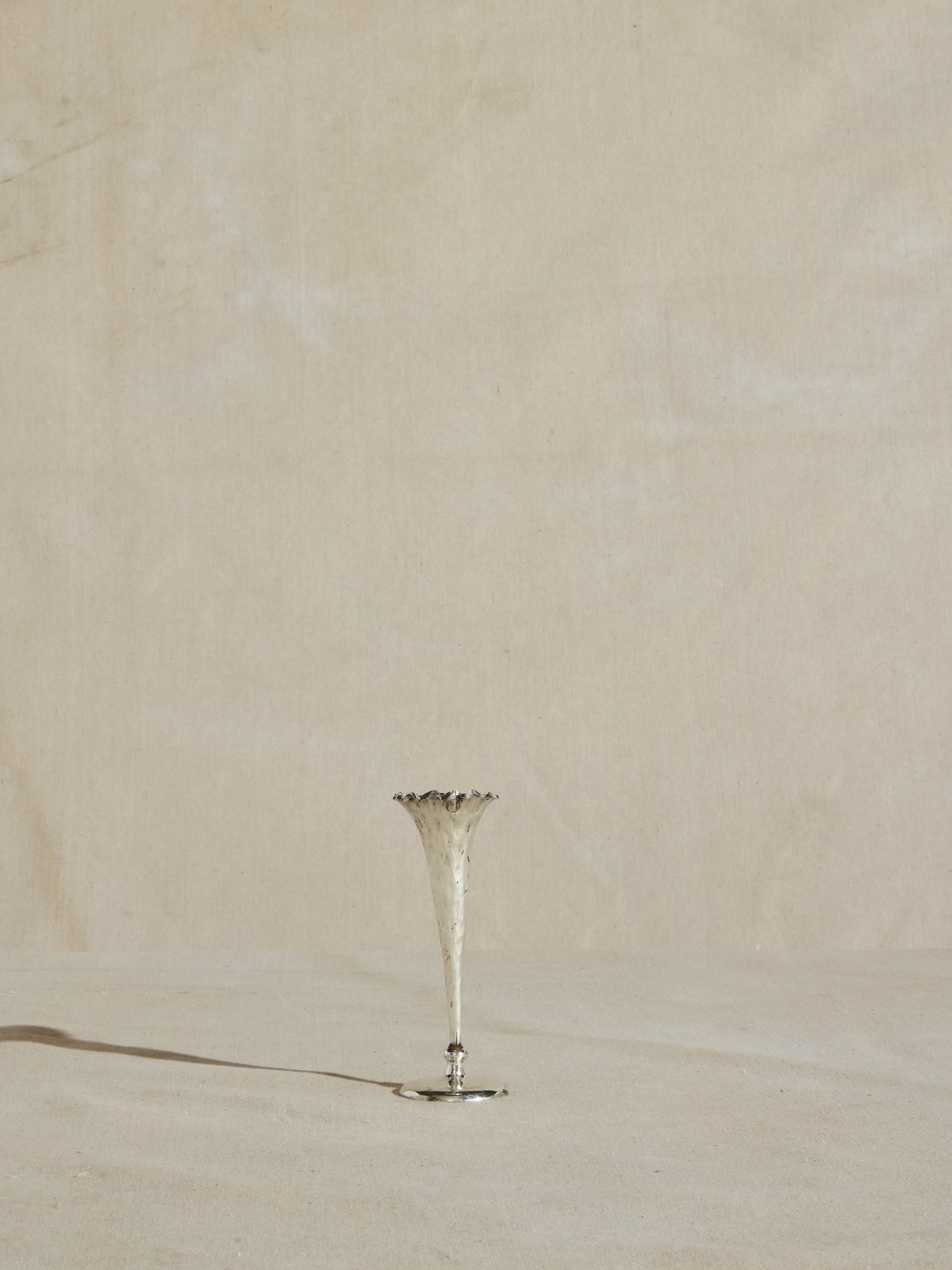 Slender sterling silver plated trumpet vase, with hammered body and wavy rim.