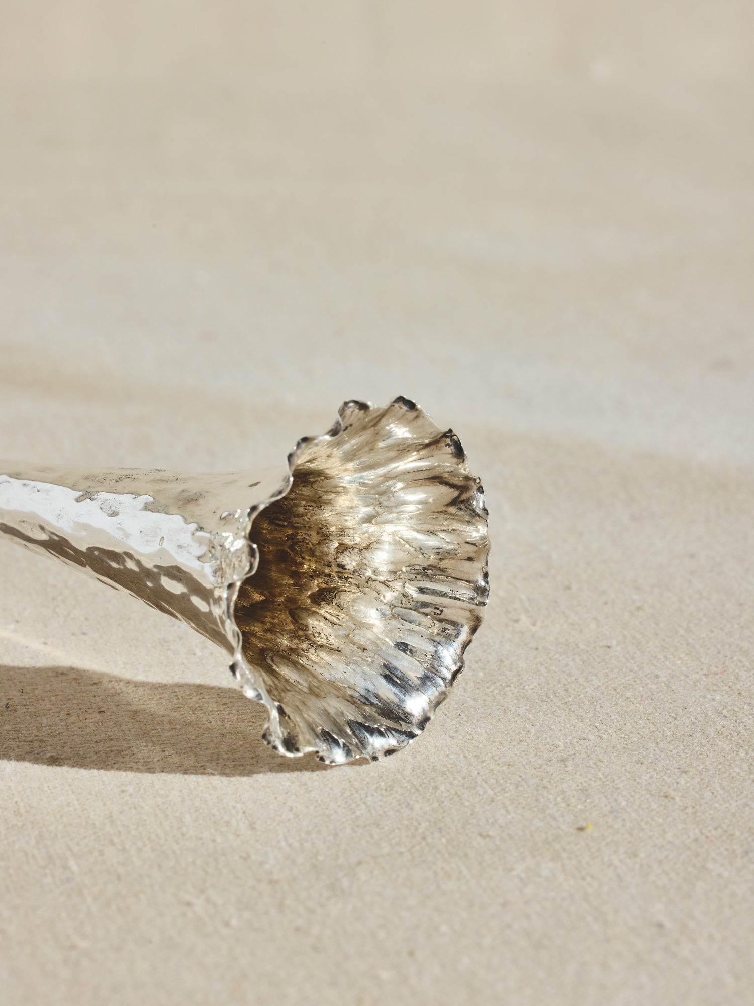 Slender sterling silver plated trumpet vase, with hammered body and wavy rim.