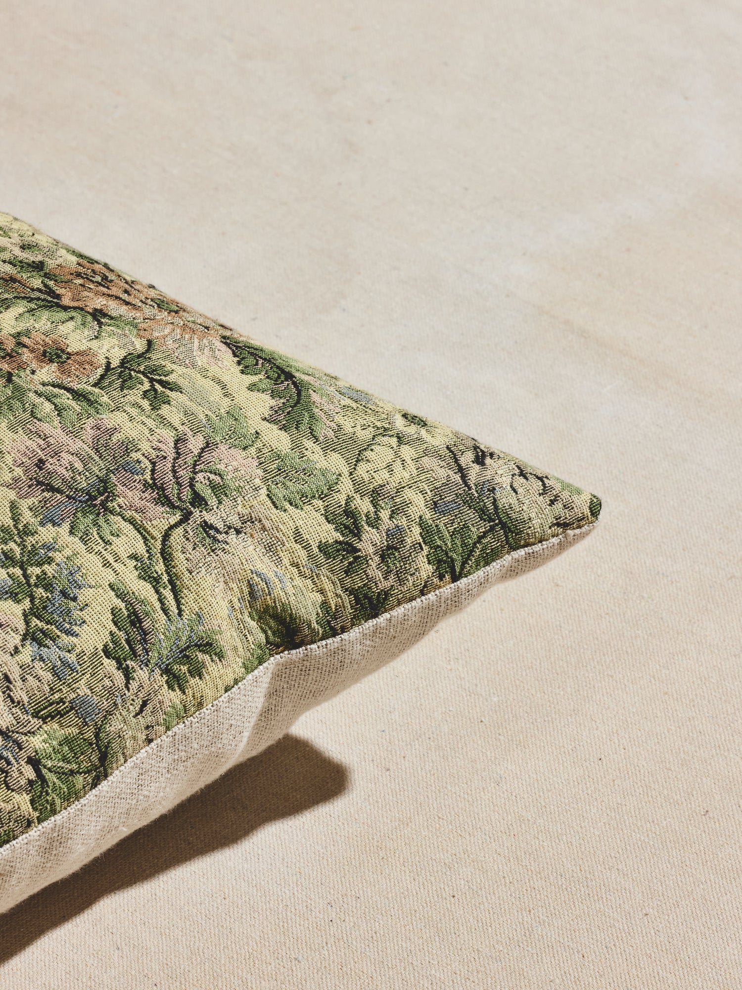 Close up view of green floral woven pillow with multi-tonal greens with pastel accents.