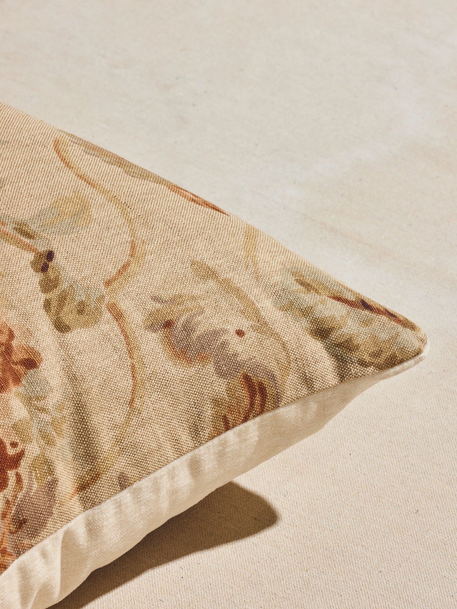 Close up of warm pastels and rust hues floral patterned woven pillow.