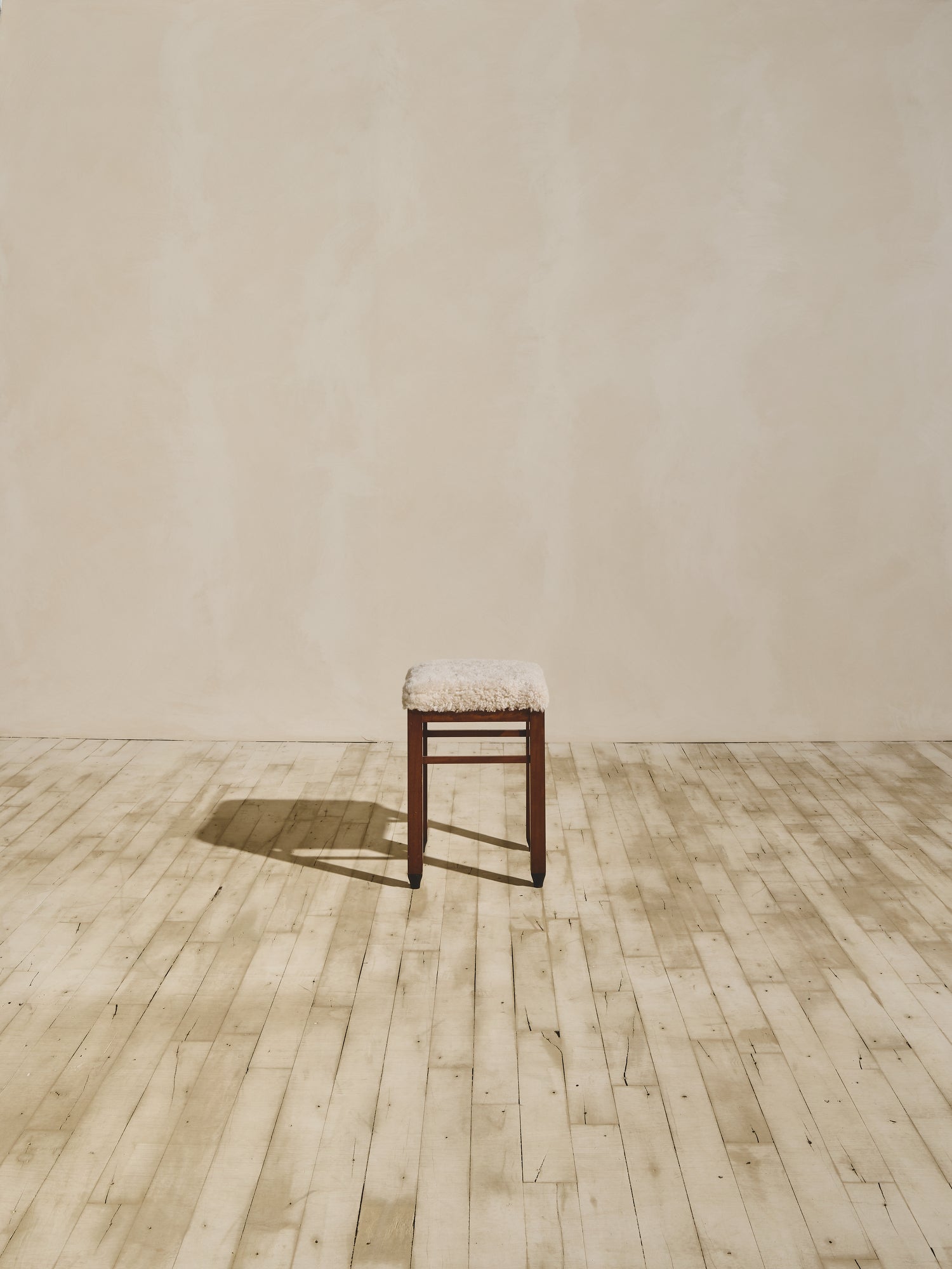 Art Deco stool that have been reupholstered in cream shearling.