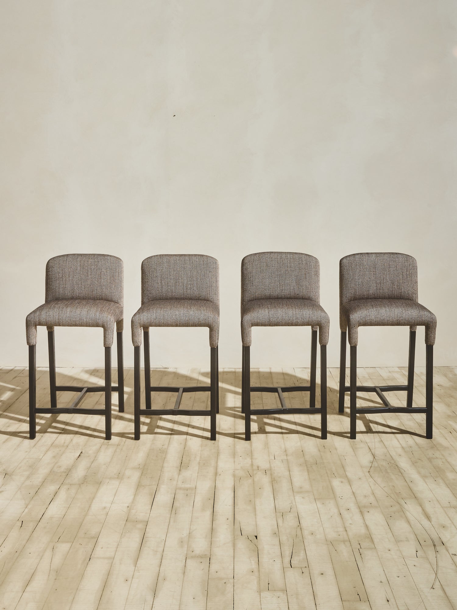 Group of Mr. Wolcott Counter Stool with curved back and sleek silhouette.