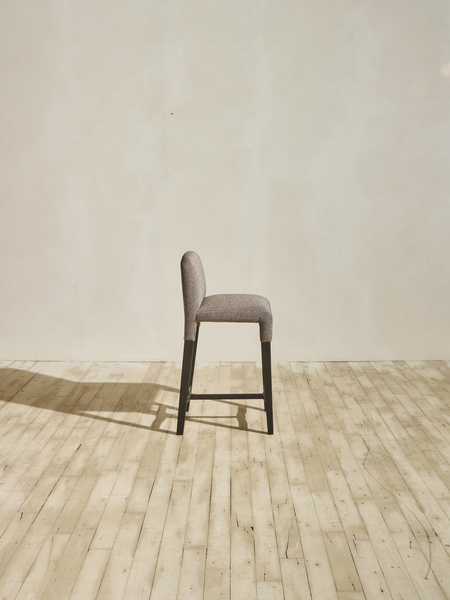 Side view of Mr. Wolcott Counter Stool with curved back and sleek silhouette.