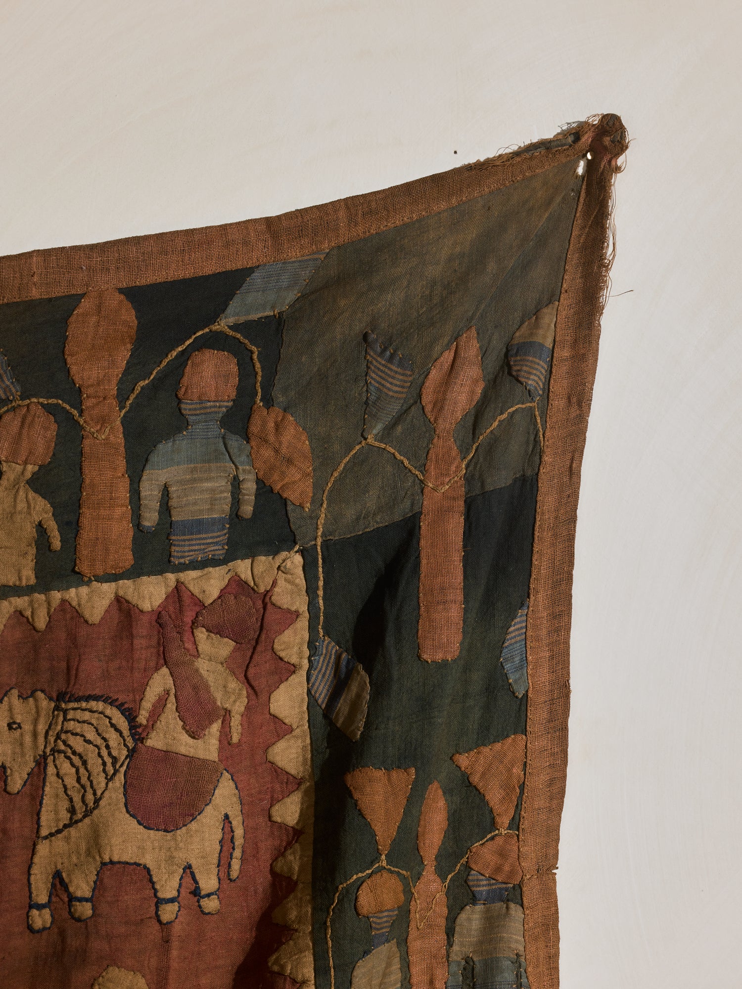 Quilted tribal tapestry, auburn, green, and yellow hues.