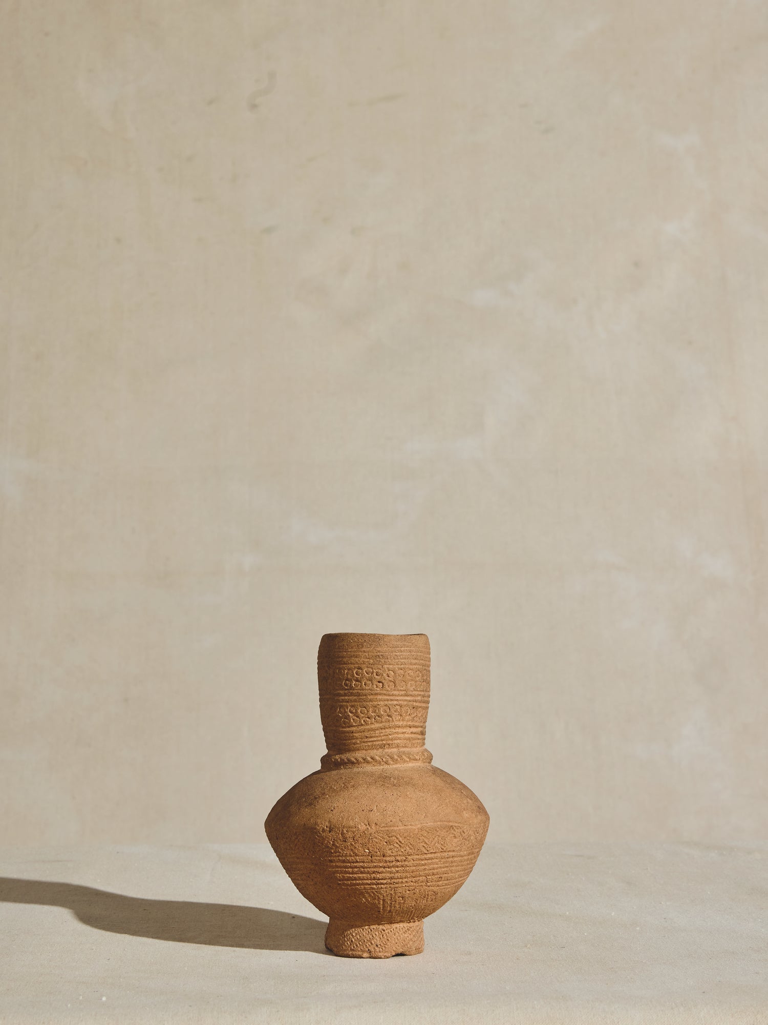 A hand carved African clay vessel, crafted in the 17th century with intricate etchings and a natural finish.