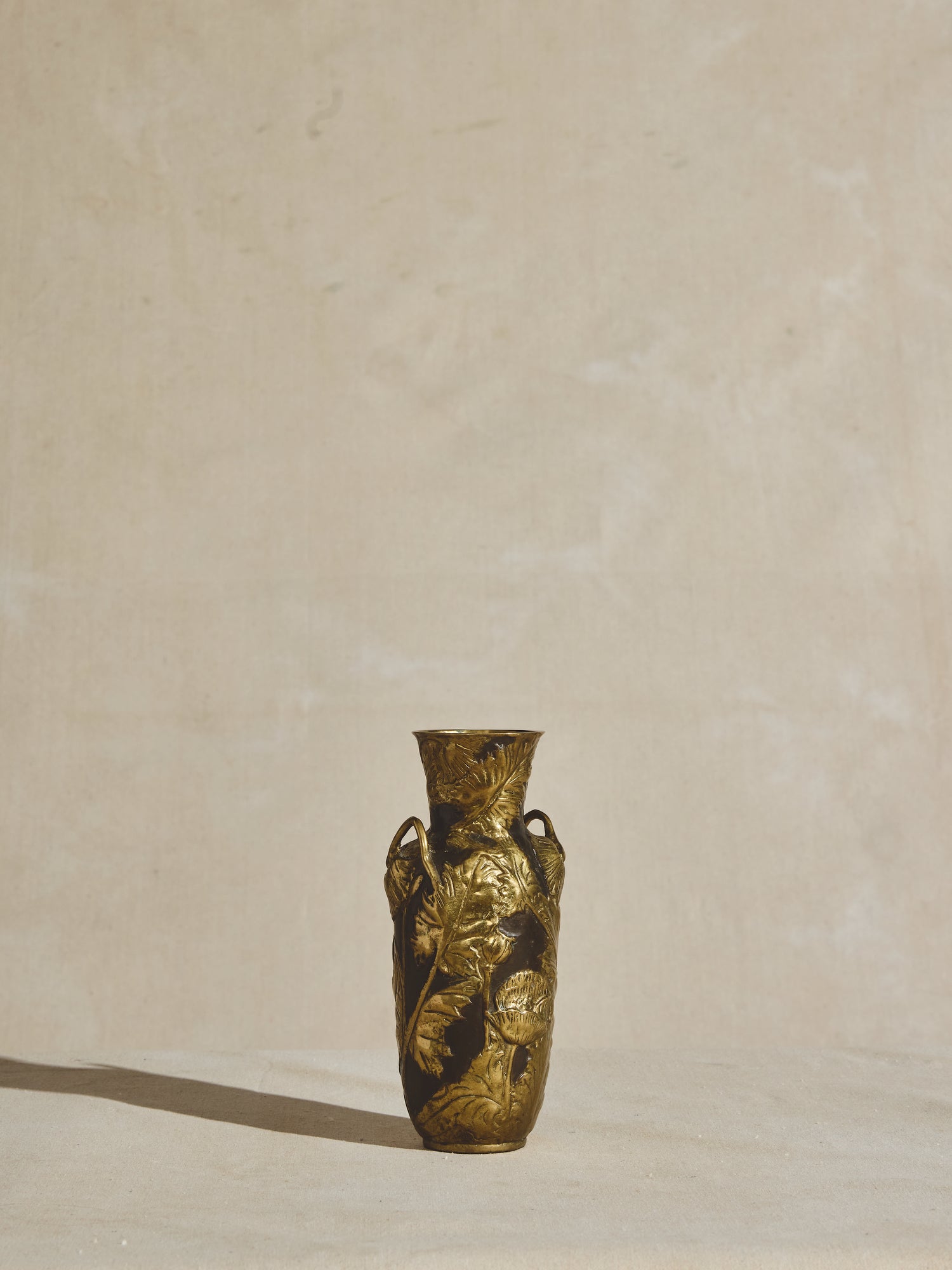 Ornate, solid bronze, art nouveau vase with tapered neck, decorative handles, and elongated body.