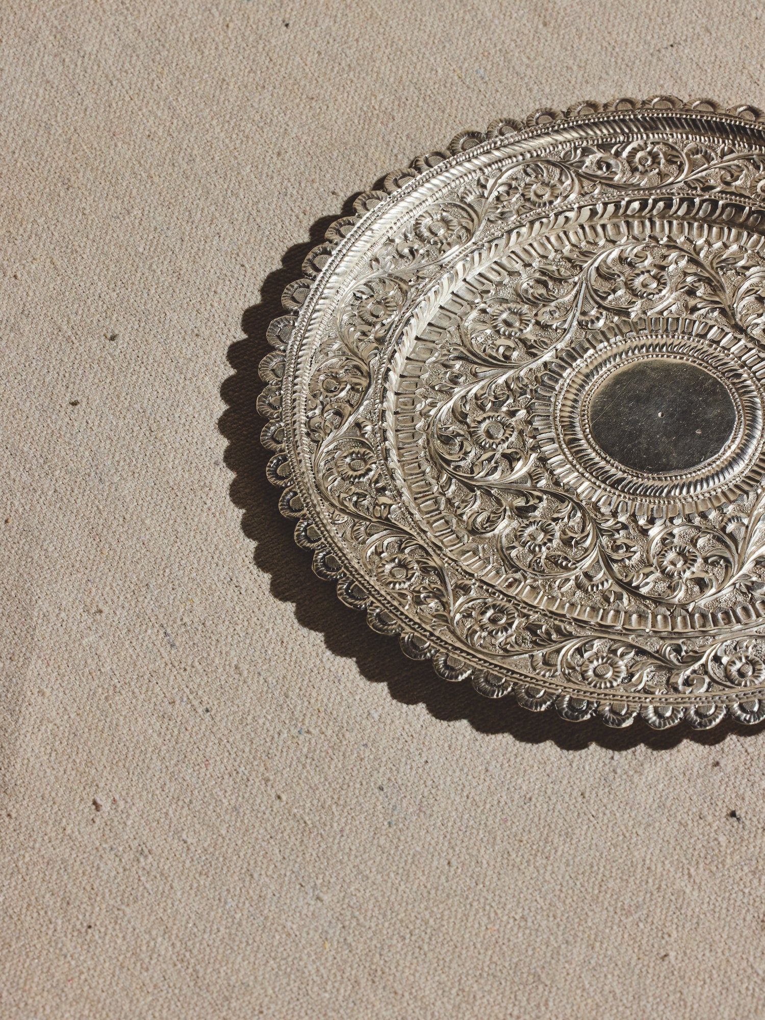 Anglo Indian hammered silver plate chased with floral designs and adorned with a decorative edge of petal-like depressions.
