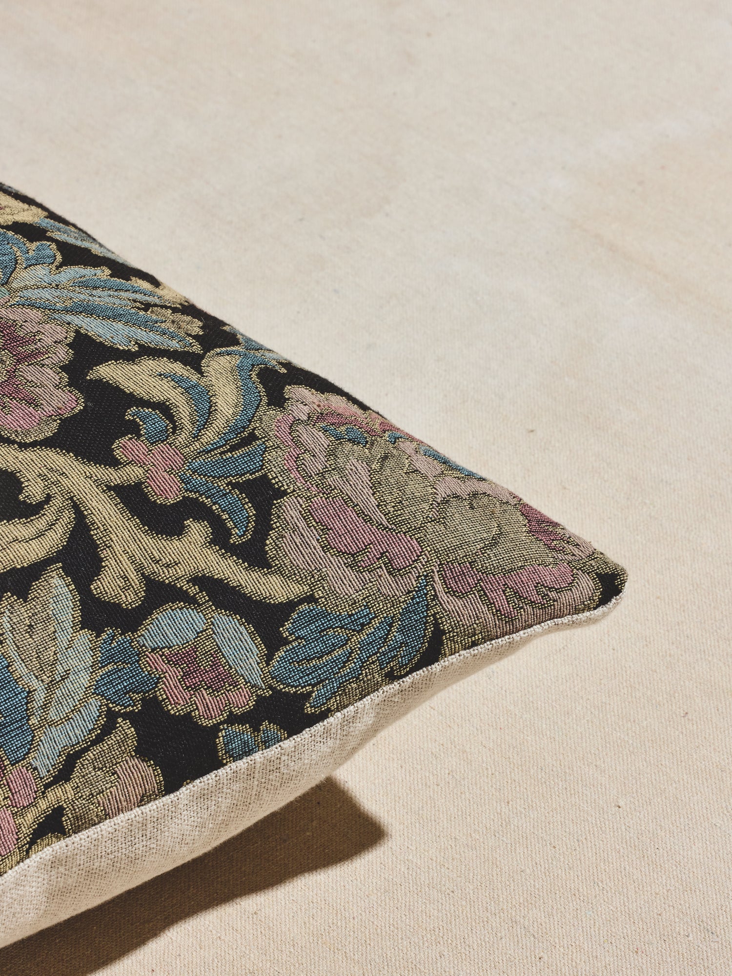 Close up of nightshade woven floral pillow with cool tones of navy, light blue, gold, and pale pinks.