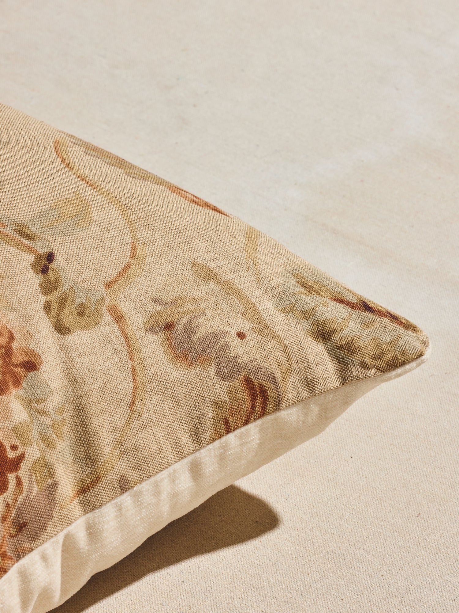 Close up of warm pastels and rust hues floral patterned woven pillow. 