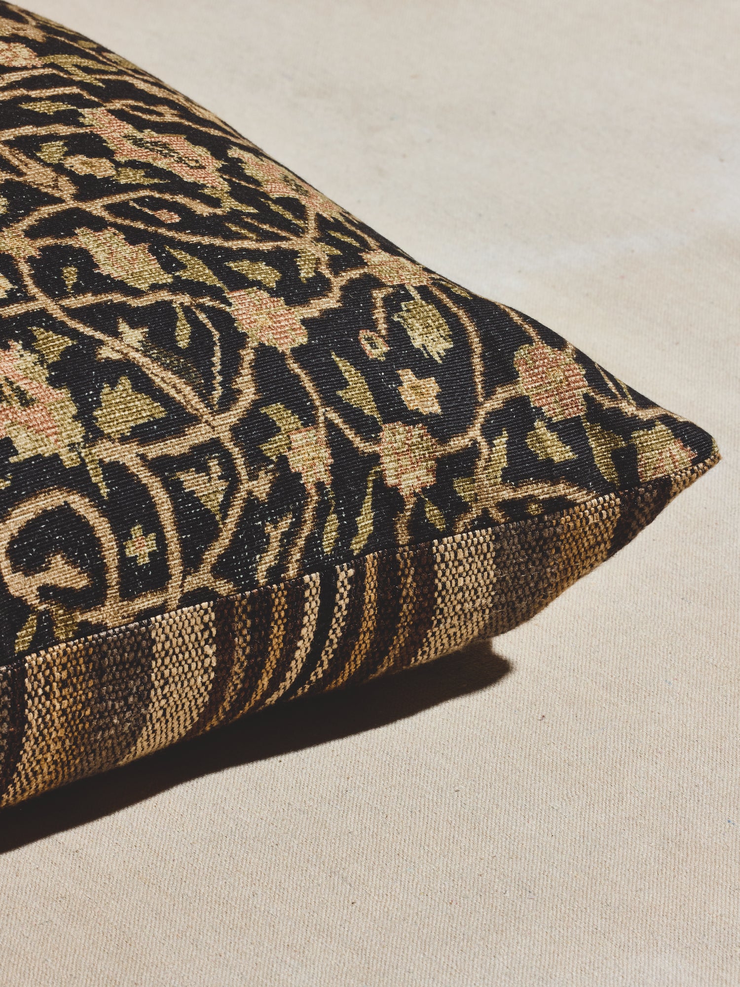 Black print woven pillow with floral motif and central medallion. 