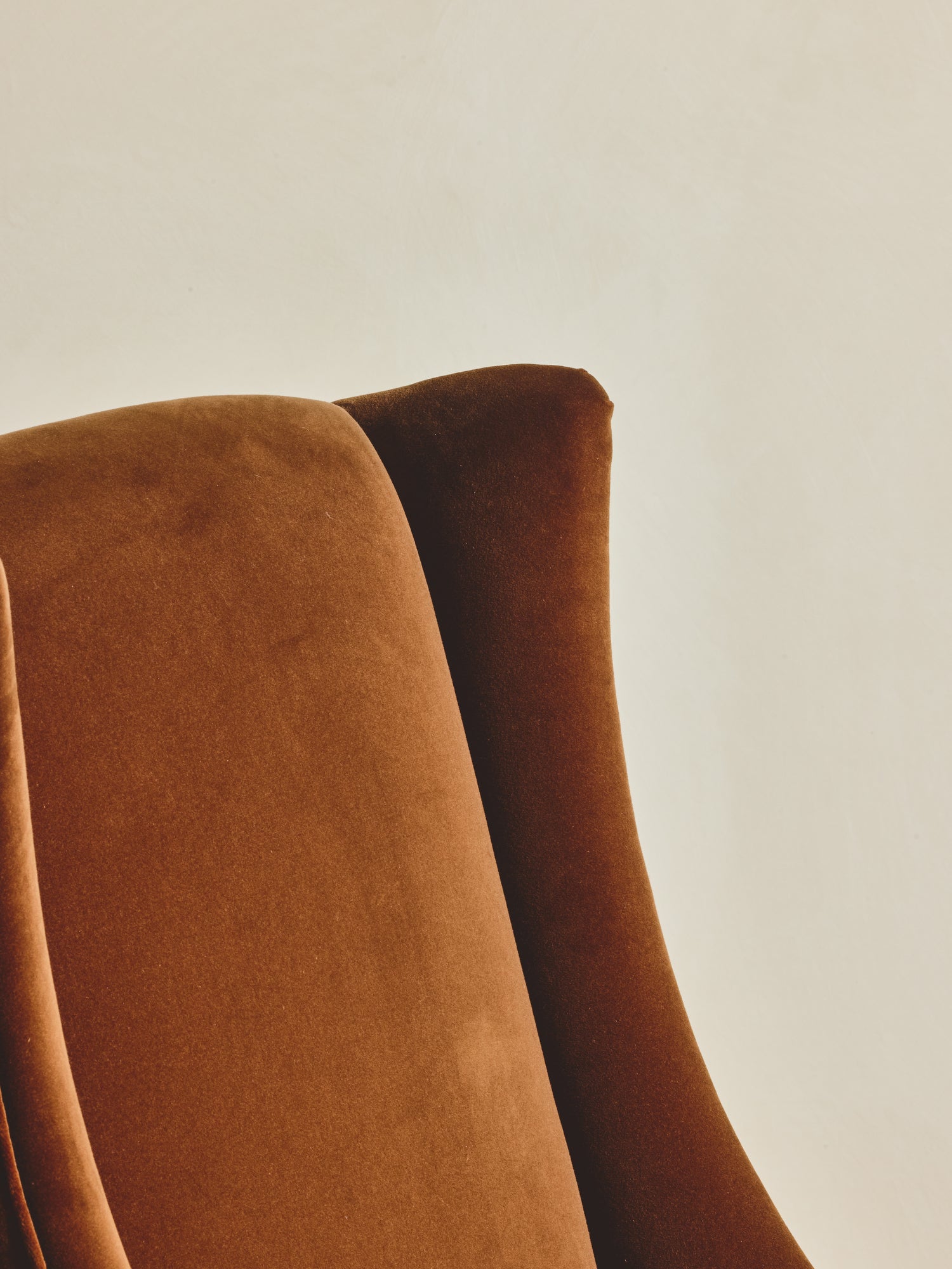 Close up of the head and arm rest of the Pavillion Chair with high back winged chair shown in our ochre fabric paired with our bronze fringe.