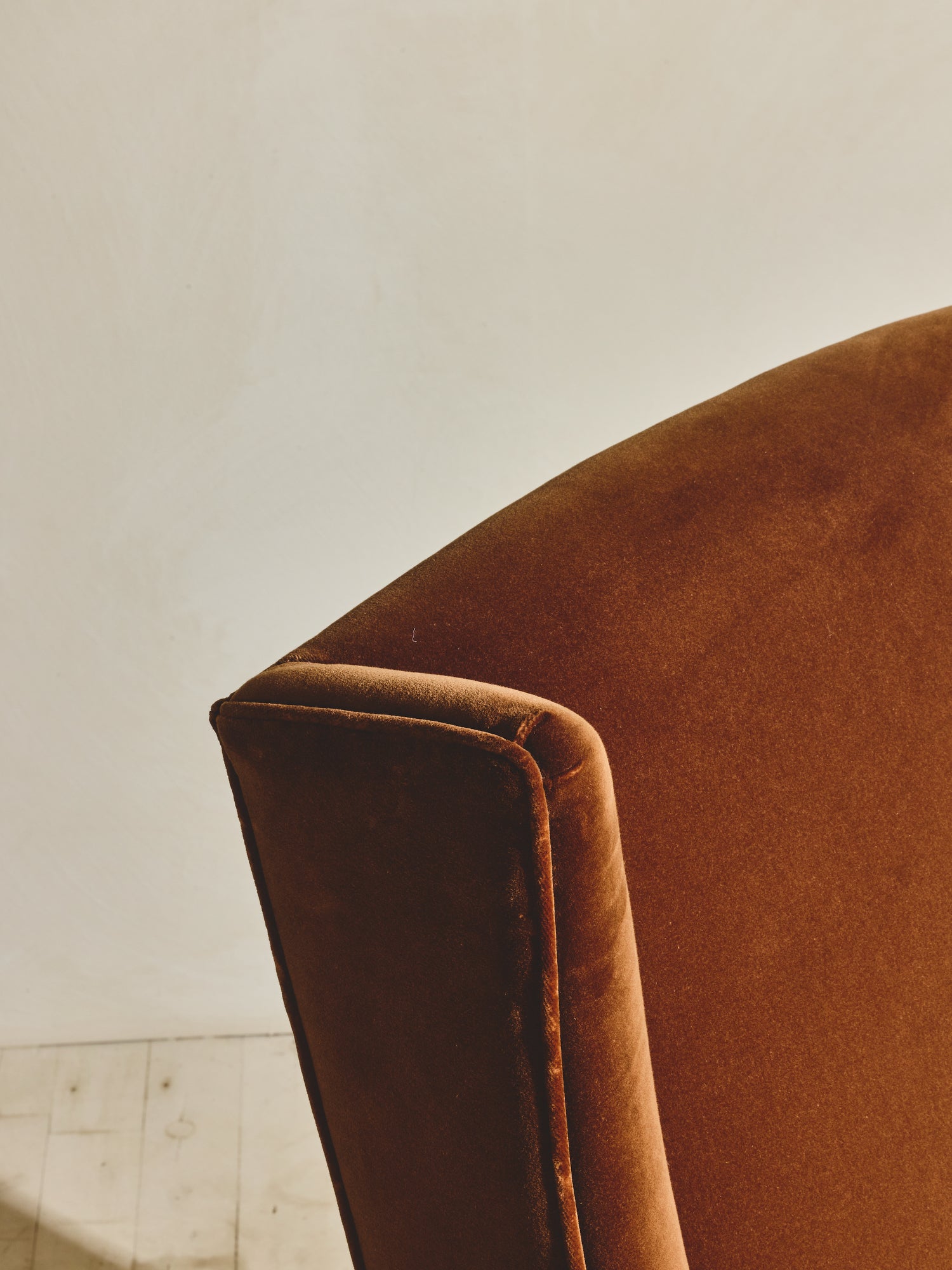 Close up of the head and arm details on the high back winged chair shown in our ochre fabric paired with our bronze fringe.