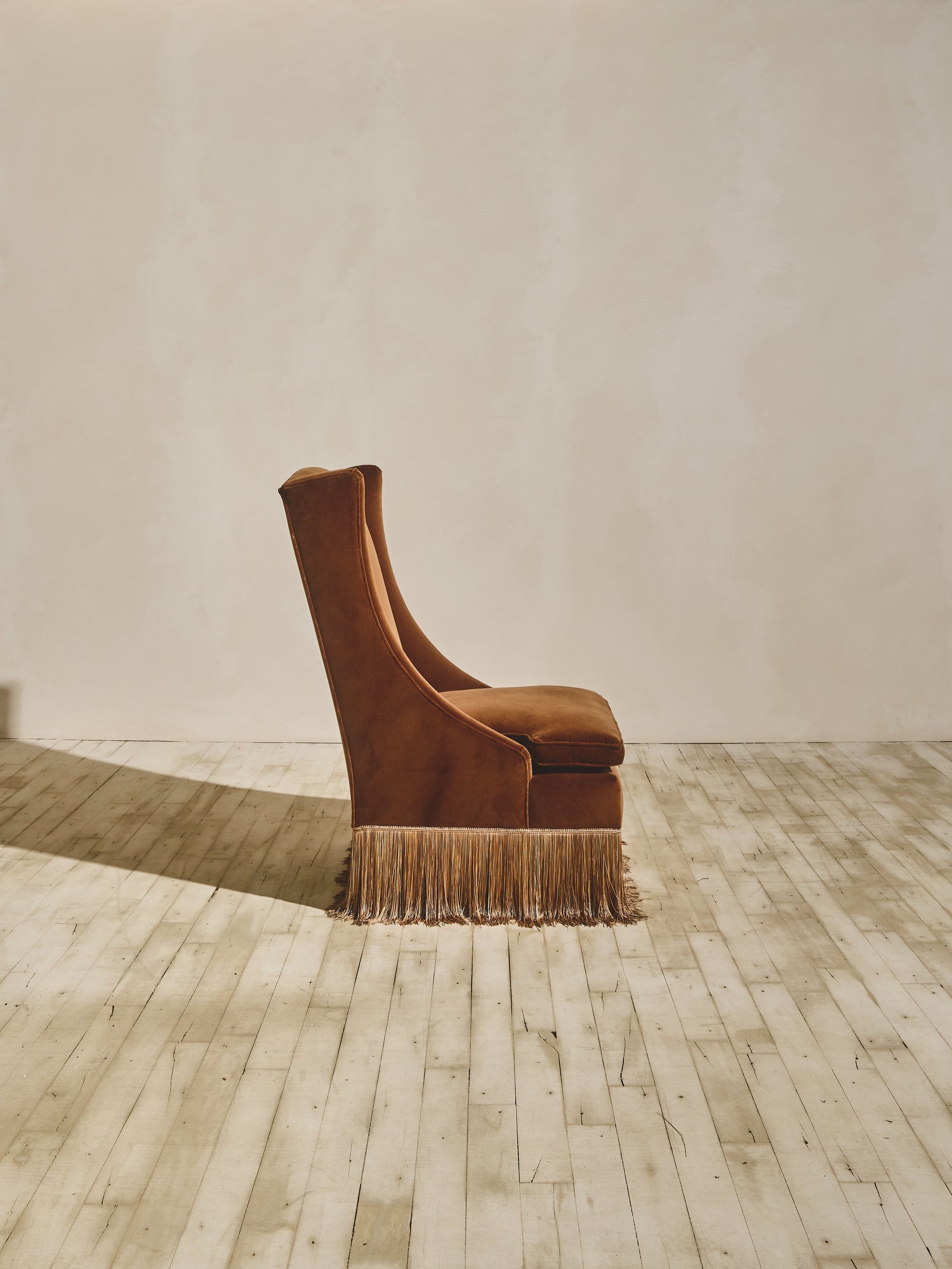 Side view of the Pavillion Chair with high back winged chair shown in our ochre fabric paired with our bronze fringe.