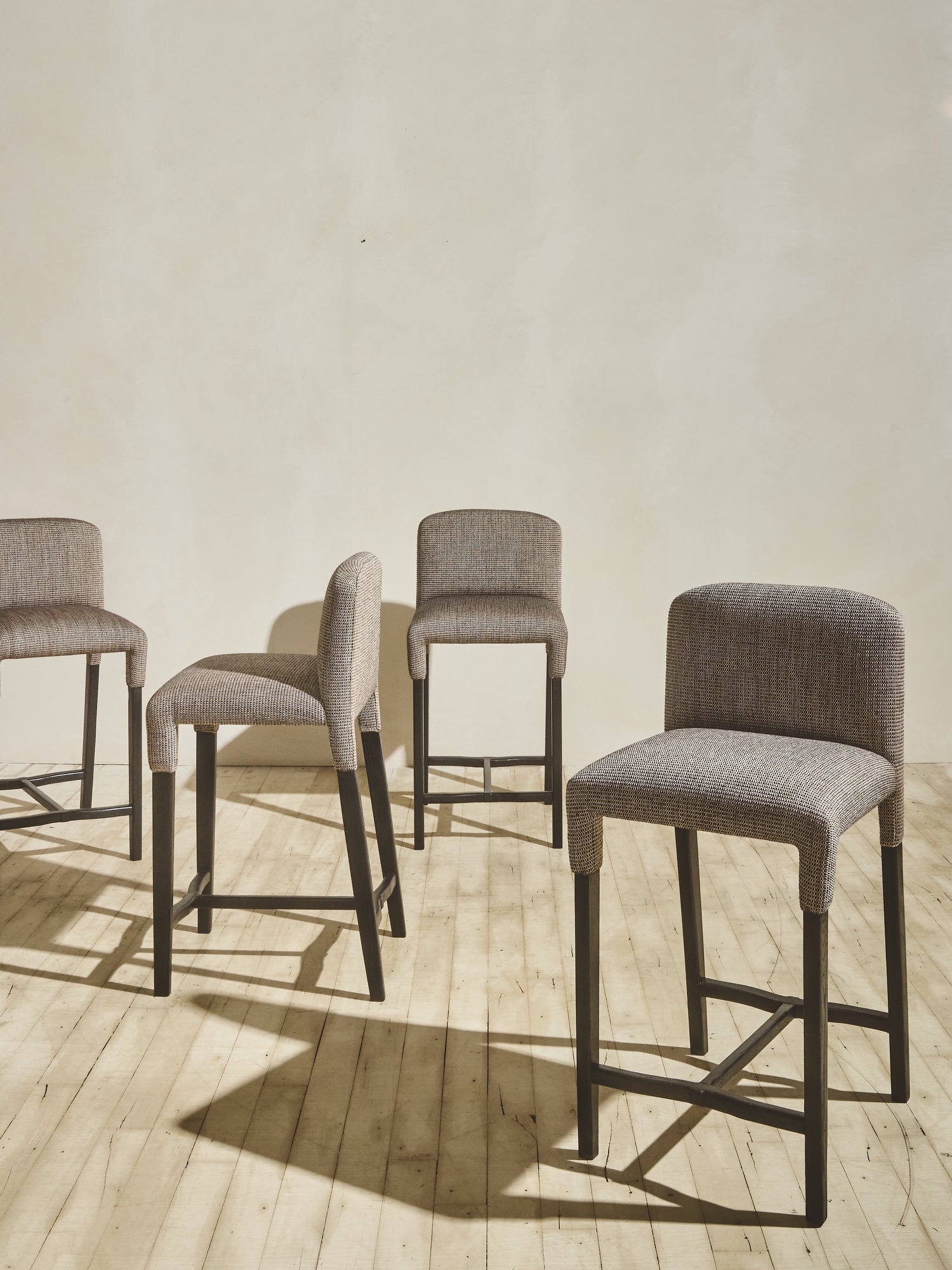 Group of Mr. Wolcott Counter Stool with curved back and sleek silhouette.