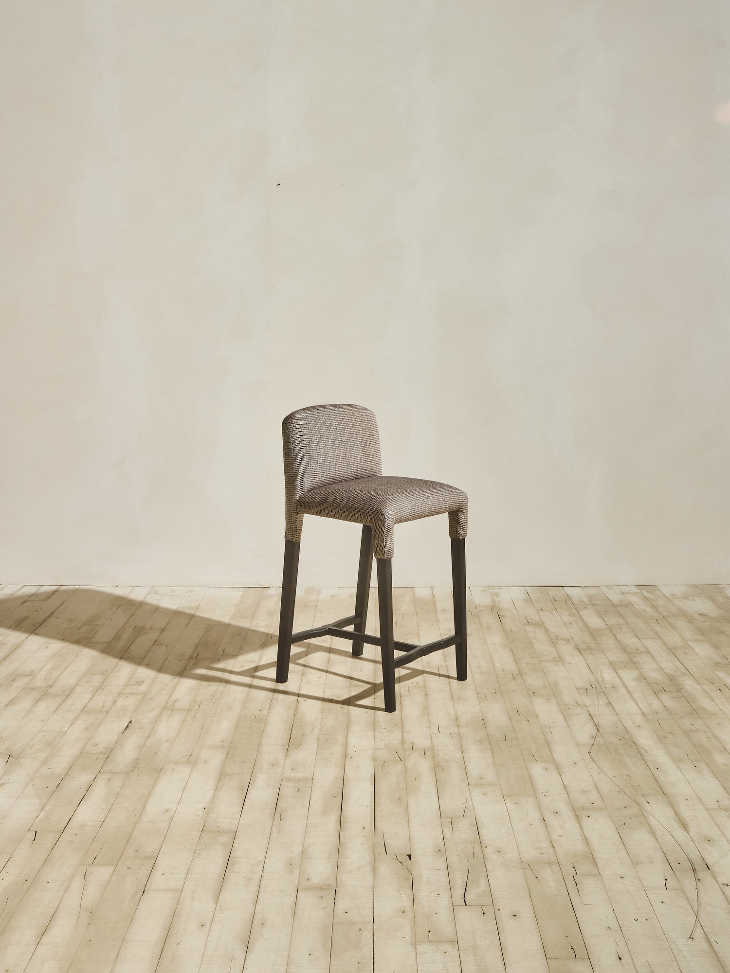 Side view of Mr. Wolcott Counter Stool with curved back and sleek silhouette.
