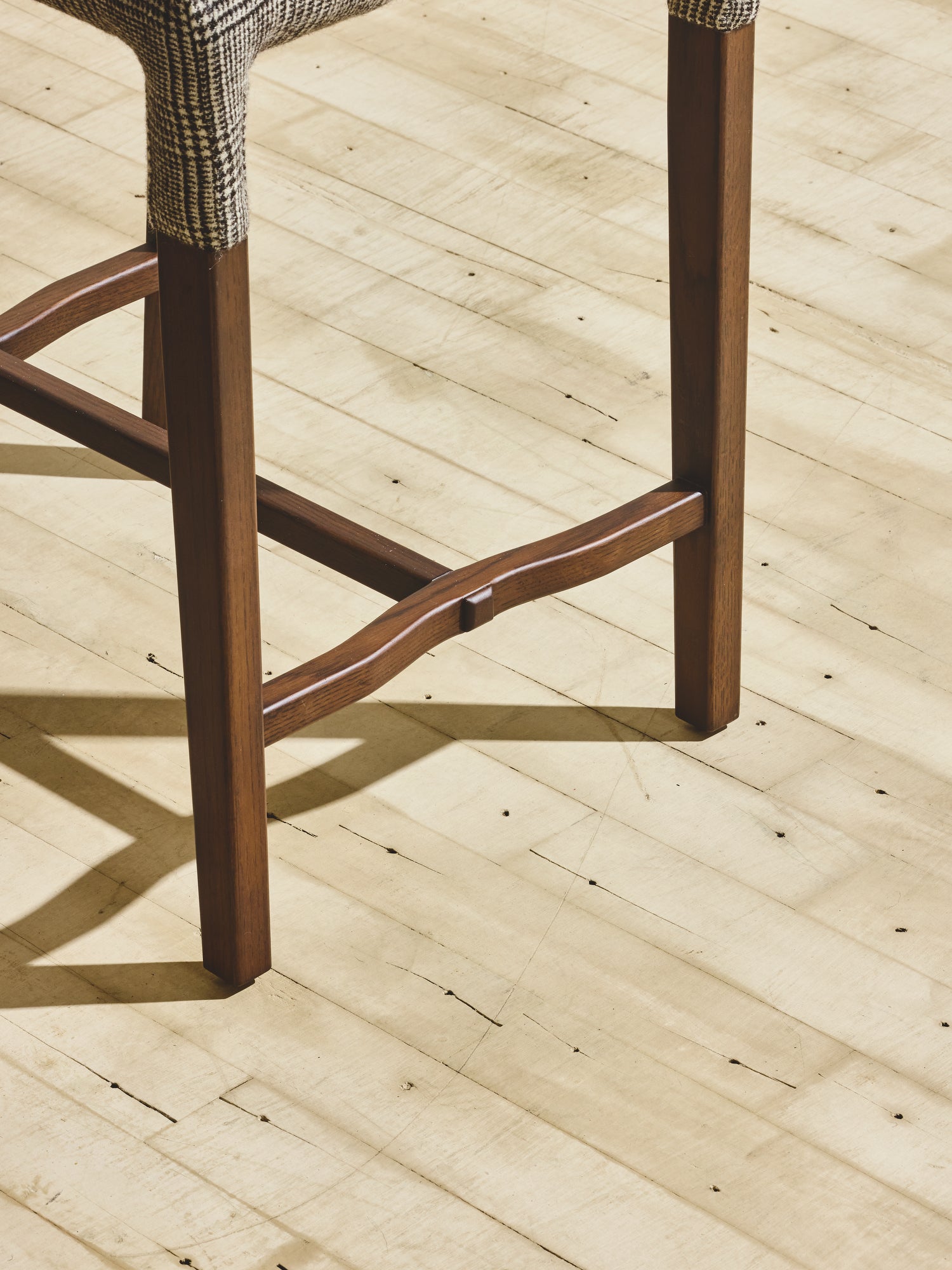 Close up of wooden legs on Mr. Wolcott Counter Stool in natural finish.