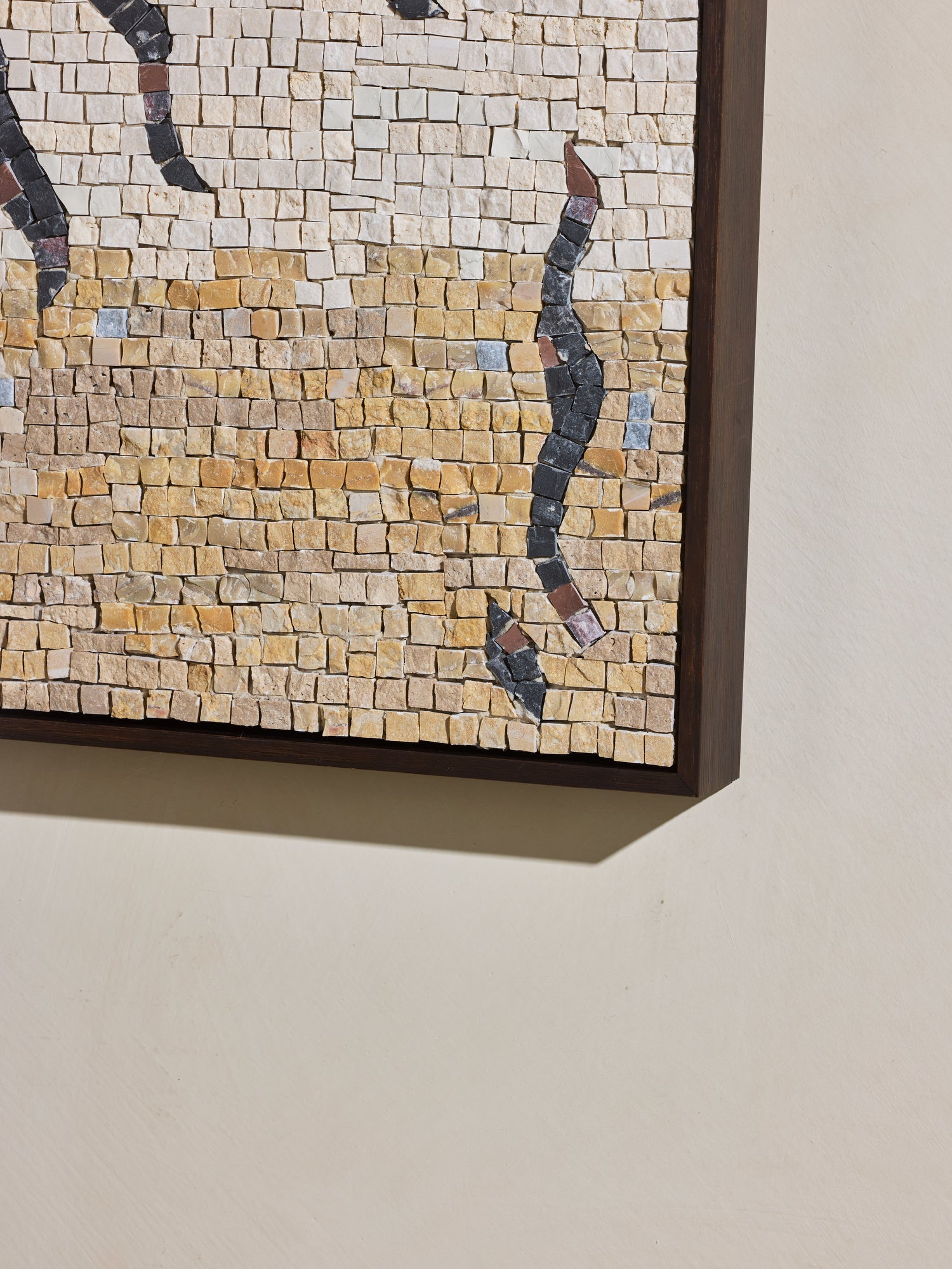 Close up of hand cut and applied stone on mosaic square stone artwork with beige, yellow, off white and black details.