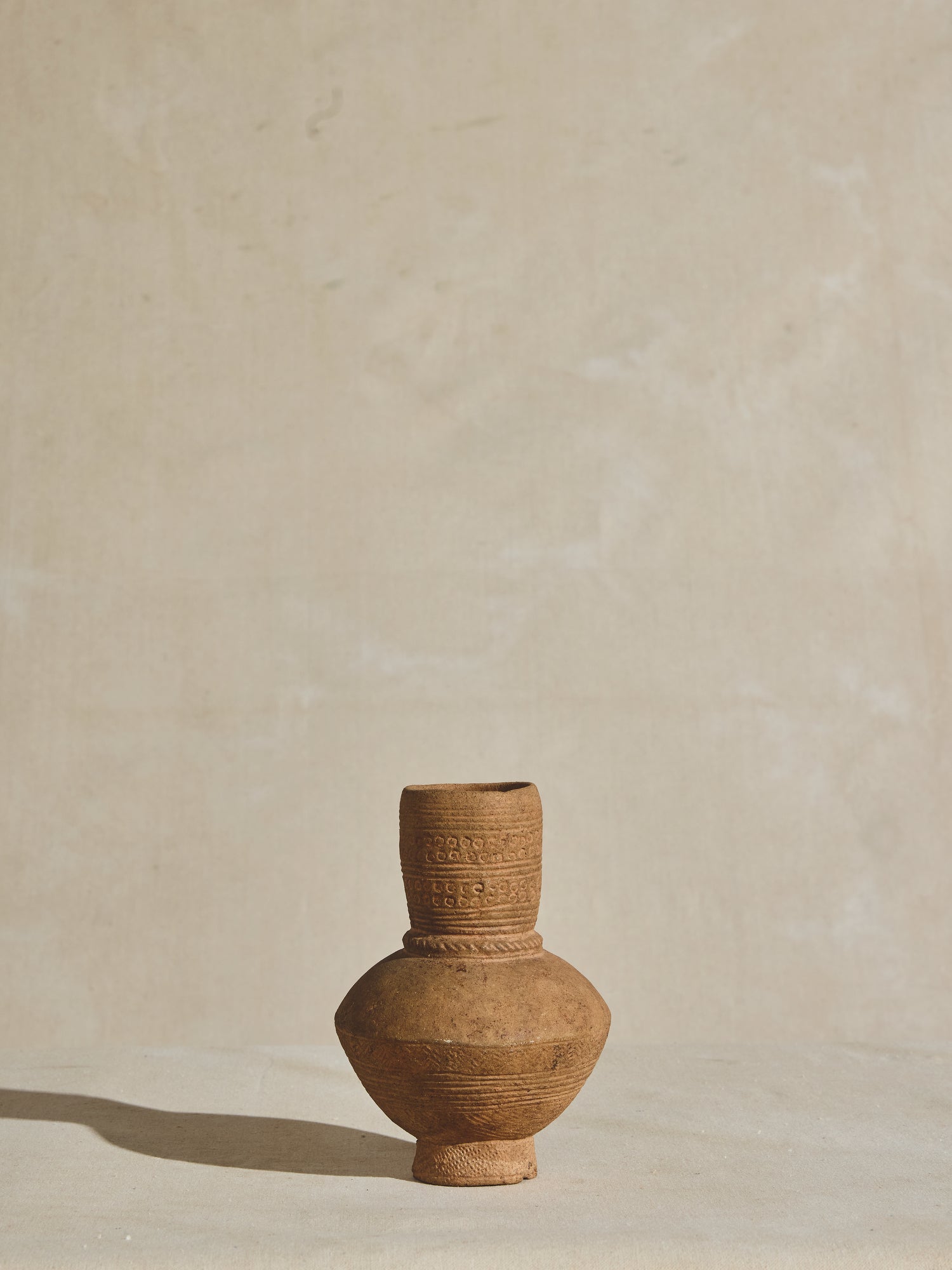 A hand carved African clay vessel, crafted in the 17th century with intricate etchings and a natural finish.