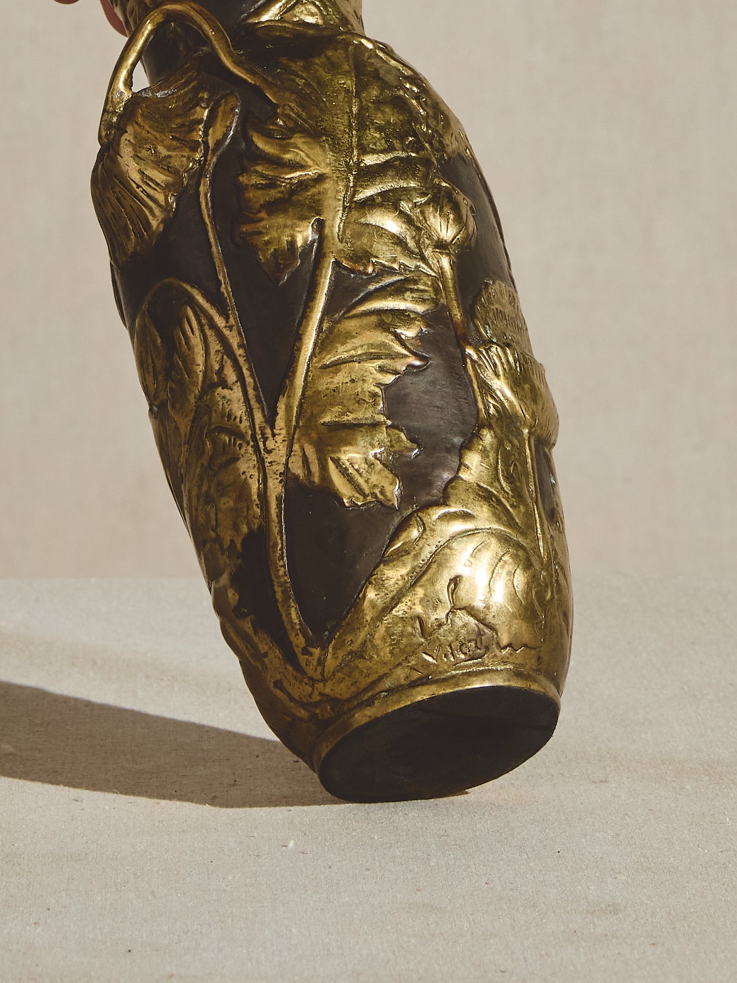 Ornate, solid bronze, art nouveau vase with tapered neck, decorative handles, and elongated body.
