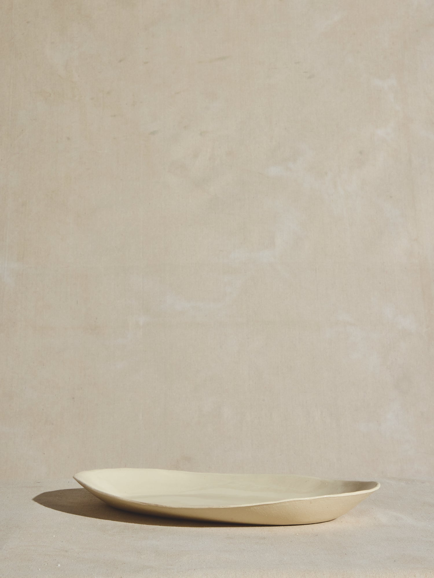 Hand thrown artisan serving platter with natural exterior shell and glazed interior.